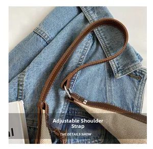 Détail de la bandoulière réglable en cuir sur un sac seau en toile avec boucle métallique