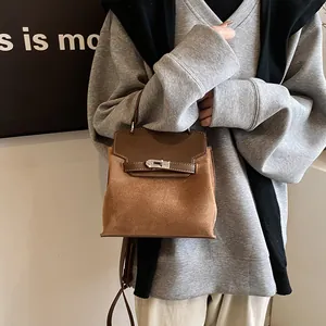 Detail of suede and leather crossbody bag with metal twist lock shown on model