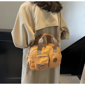 Detail of mustard yellow multi-pocket canvas crossbody bag worn by a model in a trench coat