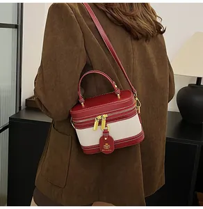 Dettaglio della borsa mini box rossa e crema con cerniere dorate su un blazer di velluto