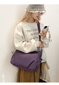 Close-up of lightweight purple nylon crossbody bag with multi-layer pockets on model