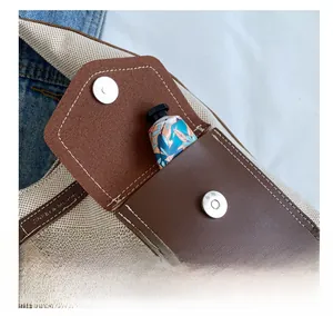Détail du sac seau en toile avec poche en cuir marron et fermoir magnétique argenté