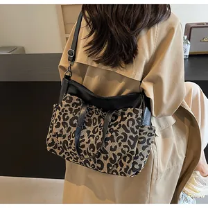 Détail du grand sac cabas à imprimé léopard avec bordures en cuir noir porté à l'épaule
