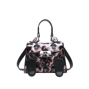 Detail of pink leopard print mini handbag featuring creative cartoon face and silver hardware