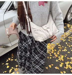 Détail d'un sac demi-lune en similicuir blanc cassé avec rivets et boucle en métal