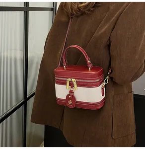 Dettaglio borsa a scatola in pelle rossa e crema con zip dorata e targhetta marchio