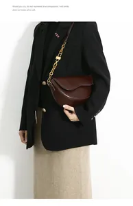 Detail view of burgundy saddle crossbody bag with chunky gold chain strap and square buckle