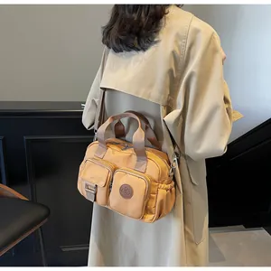 Detail of khaki nylon crossbody bag showing dual front pockets and textured material
