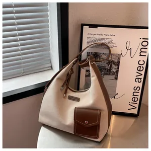 Détail du sac hobo en toile et cuir avec étiquette de marque et poche extérieure