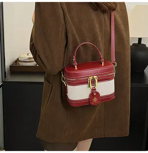 Modella che indossa una borsa retrò bicolore in tessuto beige e dettagli in pelle rossa