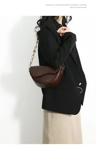 Detailed view of deep brown saddle bag with golden chunky chain and lock charm detail