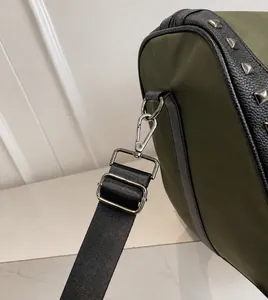 Detail of army green nylon bag with black leather trim and silver metal rivets