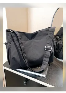 Detail of black nylon shoulder bag showing pleated texture and adjustable strap buckles