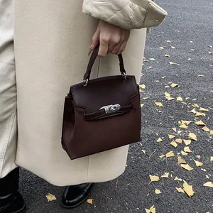Detail of dark brown Kelly style handbag with silver turn-lock in autumn setting