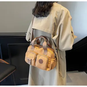 Detail view of khaki nylon crossbody bag with multi-pockets and adjustable strap on model