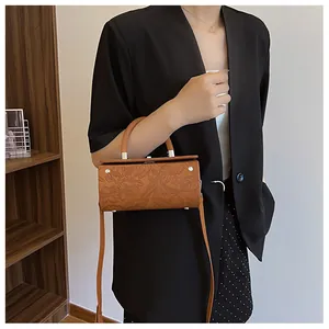 Detailed view of brown vintage cylinder bag with textured floral embossing and silver hardware