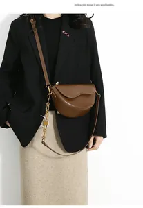 Close-up of saddle bag with sleek leather texture, gold chain and adjustable strap