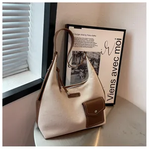 Détails de la toile beige et des coutures en cuir marron sur le sac seau hobo