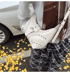 Détail du sac croissant crème avec clous argentés et boucles métalliques en décor d'automne
