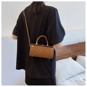 Detail view of vintage brown cylindrical bag with floral embossing and slim strap