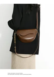 Detail of dark brown saddle bag with wavy flap, gold chain and slim leather shoulder strap