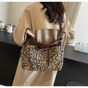 Détail du sac cabas imprimé léopard avec anses en cuir marron porté par un mannequin