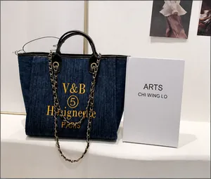 Detail der dunkelblauen Denim-Einkaufstasche mit Goldkette und großem Fassungsvermögen