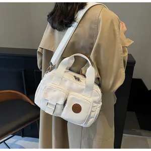 Detail of white canvas crossbody bag with dual zipper pockets and wide fabric strap
