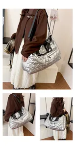Gros plan sur le tissu argenté matelassé et la sangle noire du sac de voyage