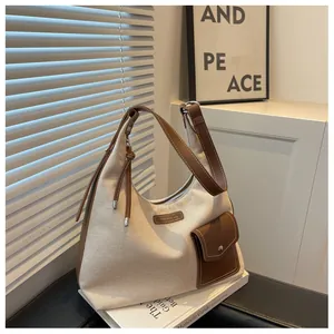 Détail du sac seau en toile avec finitions en cuir marron et bandoulière réglable