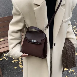 Close-up of brown suede and leather stitching handbag with metallic clasp