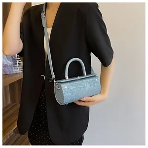 Blue cylindrical baguette bag with floral embossing and silver hardware on model