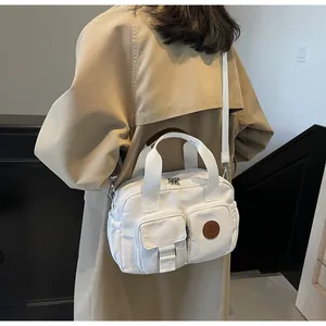 Detail of white canvas crossbody bag with multiple zip pockets and adjustable strap