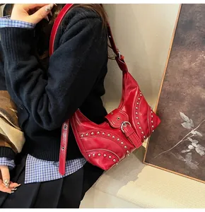 Détail du sac à main rouge en cuir brillant avec clous argentés et boucle de ceinture