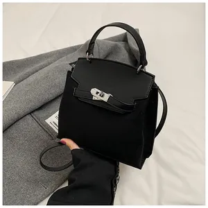 Detail showing matte frosted leather stitching and gold metal turn-lock on black bag