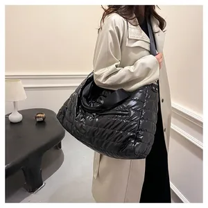 Détail d'un grand sac cabas noir matelassé avec une finition brillante et des anses tissées