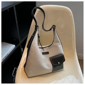 Détail d'un sac seau en toile avec garniture en cuir noir sur une chaise blanche