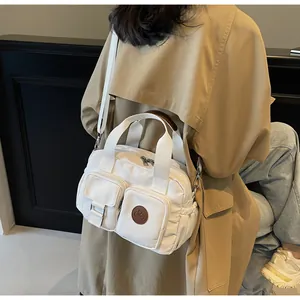Detailed view of white canvas crossbody bag with multiple pockets and adjustable strap