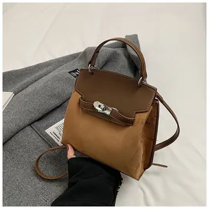 Close-up of brown suede and leather splicing texture with silver metal clasp on handbag