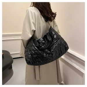 Gros plan du grand sac cabas noir matelassé avec bandoulière réglable porté par un mannequin