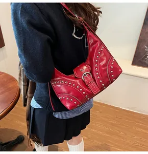 Détail du sac à bandoulière en cuir rouge avec clous argentés et boucles déco