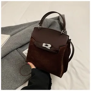 Detailed close-up of dark brown velvet Kelly bag with silver twist lock and smooth leather