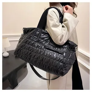 Détail d'un grand sac cabas matelassé noir avec bandoulière large sur manteau beige
