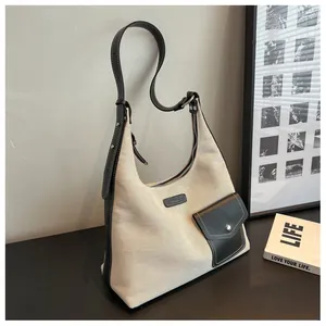 Détail du sac hobo en toile avec garniture en cuir noir et poche avant à boucle métallique