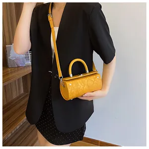 Detail of yellow cylindrical bag featuring embossed floral texture and silver hardware
