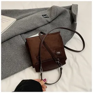 Close-up of brown suede Kelly bag on grey coat with adjustable shoulder strap detail