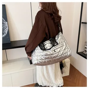 Vue détaillée du sac fourre-tout argenté matelassé avec anses noires et poche zippée