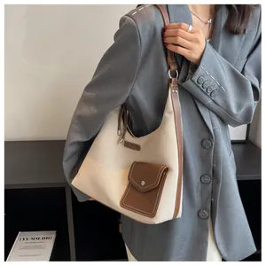 Détail du sac hobo en toile avec garniture en cuir marron et poche sur un blazer gris