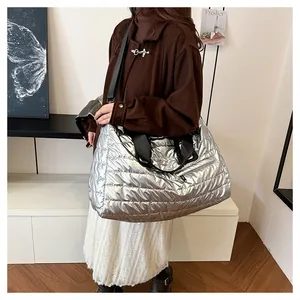 Détail du sac matelassé argenté montrant le tissu métallisé et la bandoulière noire