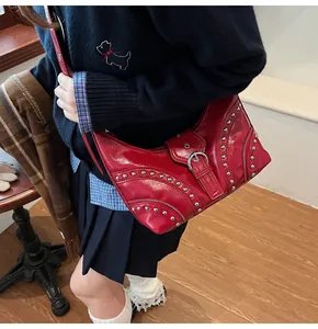 Détail du sac à bandoulière en cuir verni rouge avec clous argentés et fermetures